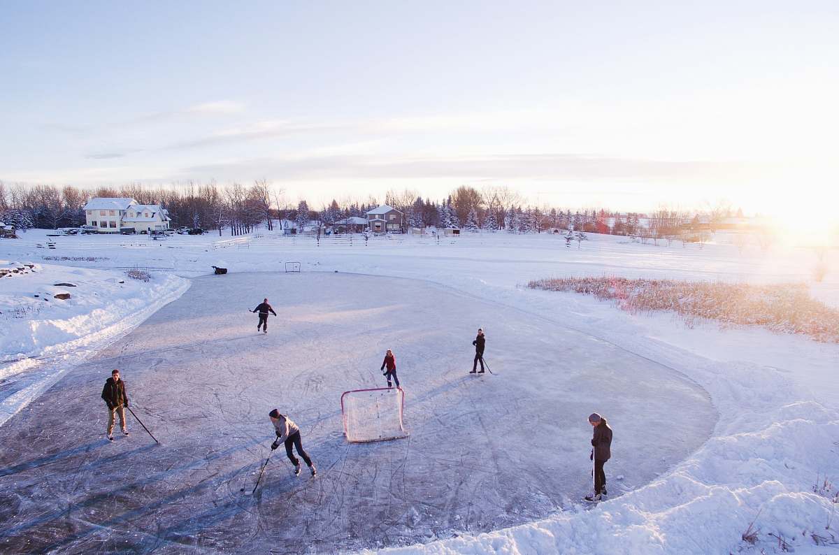 ice skating group of people playing outdoor hockey during winter game